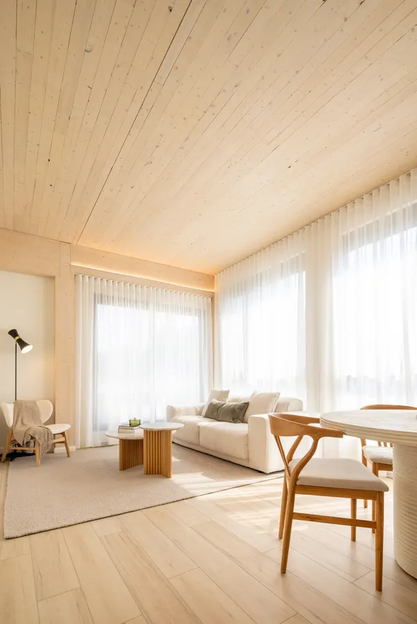 Living and dining room under an exposed CLT ceiling at ANDAS