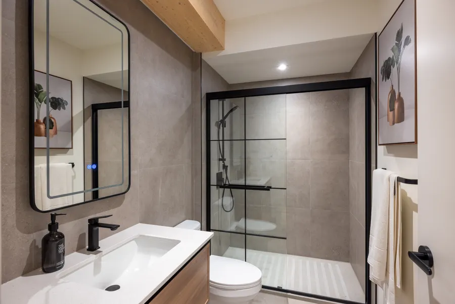 Bathroom with curbless quartz shower and backlit mirror