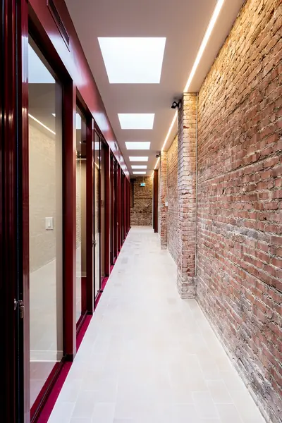 Corridor of private offices with burgundy frames and original brick