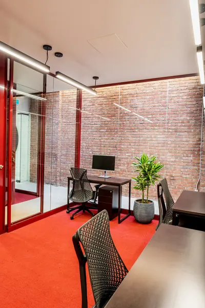 Private office with red carpet and a brick wall