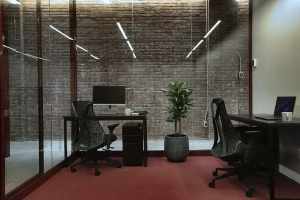 Private office behind glass with a brick wall and a plant